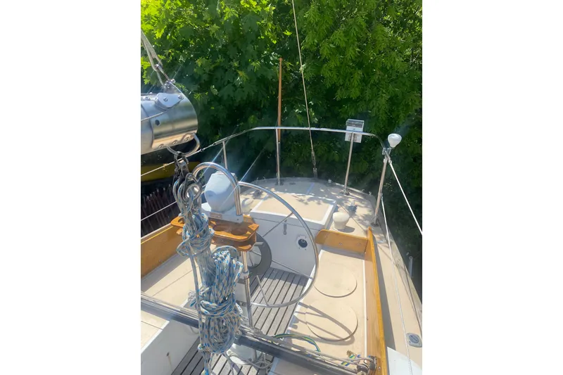 Slide: The Image of 1982 Bristol 40 sailboat deck with ropes and steering wheel, surrounded by greenery. - 15