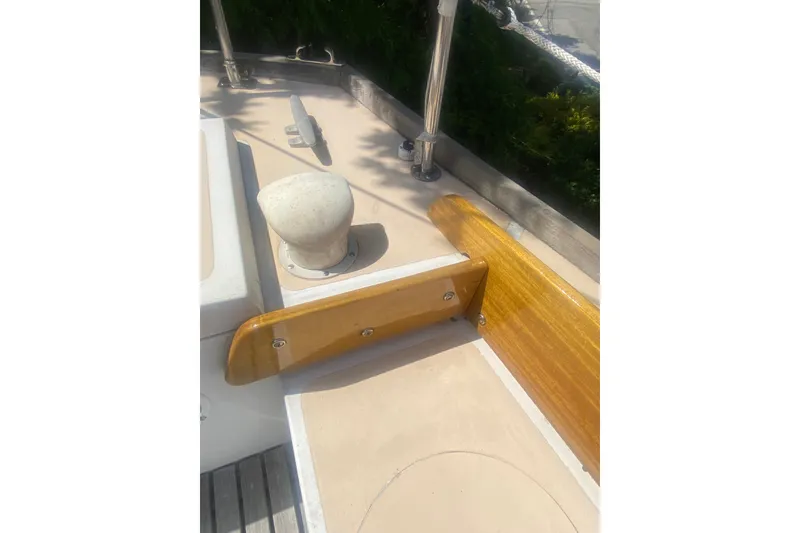 Slide: The Image of 1982 Bristol 40 sailboat deck with wooden trim and cleat in sunlight. - 13