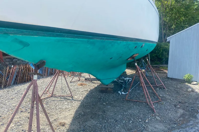 Slide: The Image of 1982 Bristol 40 sailboat on stands, hull painted turquoise, outdoors near a shed. - 24