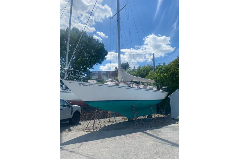 The Image of 1982 Bristol 40 sailboat on stands, clear sky, trees in background. - 1