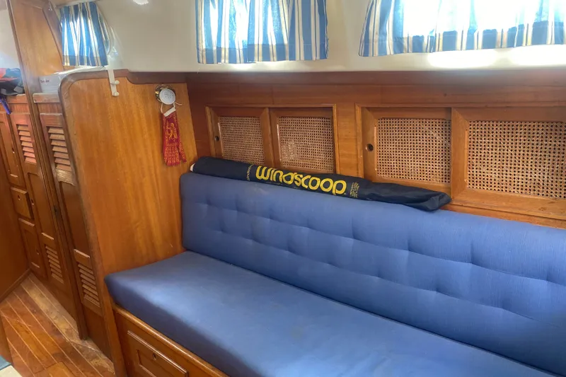 Slide: The Image of Interior of 1982 Bristol 40 sailboat with blue cushioned seating and wooden cabinetry. - 7
