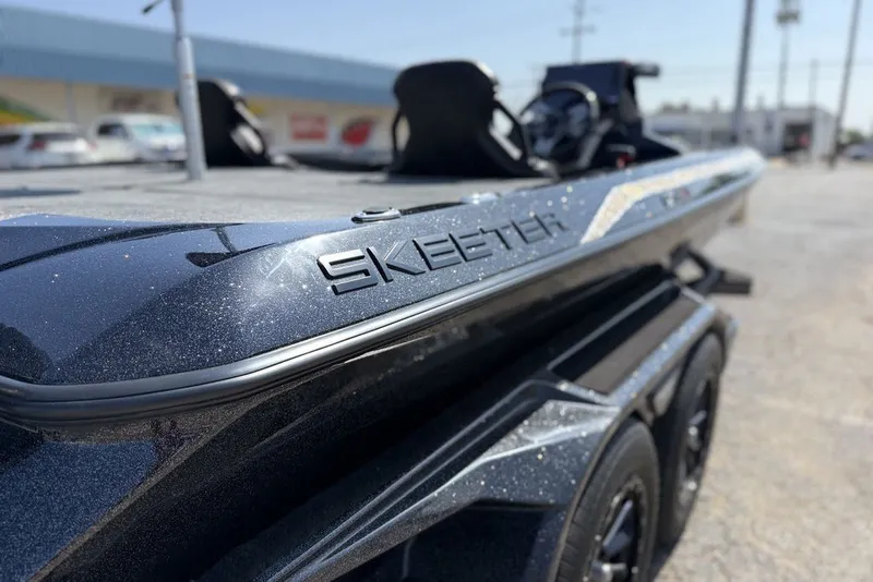 Slide: The Image of 2027 Skeeter FXE21 Limited boat, sleek design with metallic finish, parked outdoors. - 19