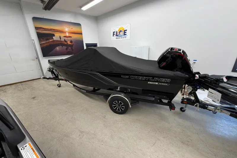 Slide: The Image of 2026 Crestliner XFC 179 boat with cover in showroom, featuring sleek design and modern outboard motor. - 1