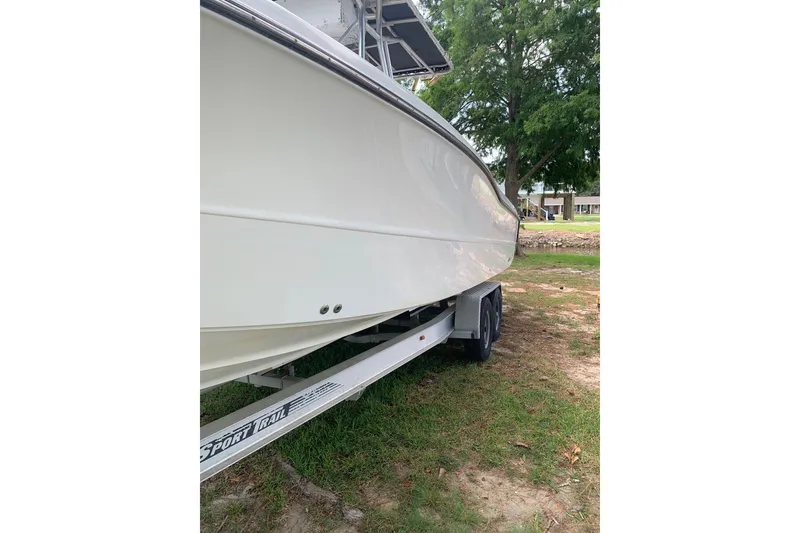 Slide: The Image of 2005 Triton 2895 CC boat on trailer, side view, parked on grass. - 6