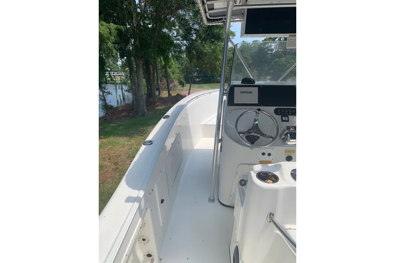 Slide: The Image of 2005 Triton 2895 CC boat interior with steering wheel and control panel, docked near trees. - 12