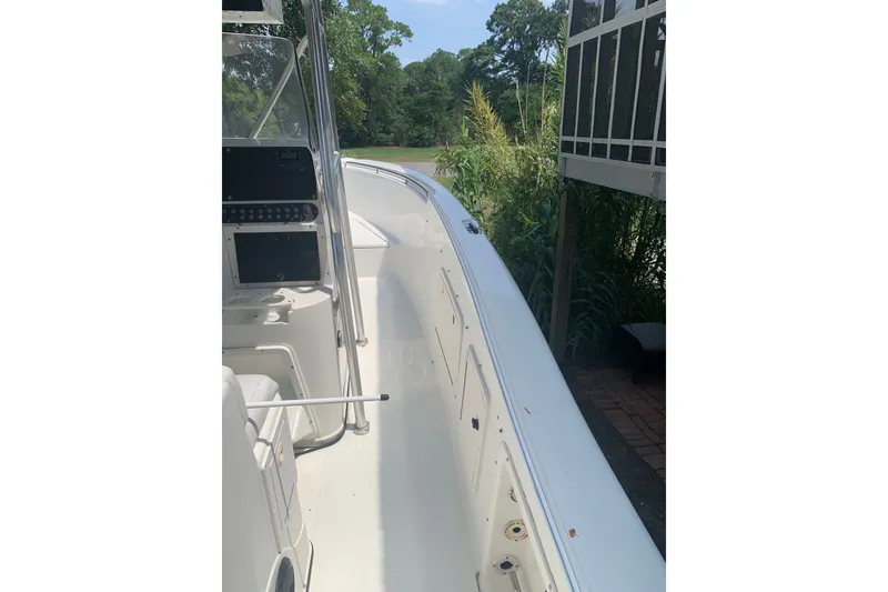 Slide: The Image of 2005 Triton 2895 CC boat interior with console, surrounded by greenery. - 13