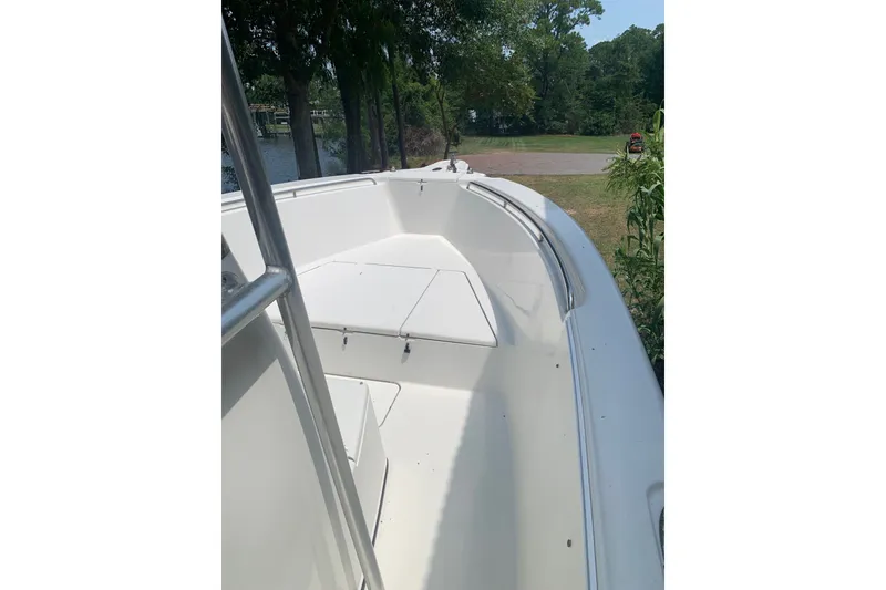 Slide: The Image of 2005 Triton 2895 CC boat deck with seating, surrounded by trees and greenery. - 15
