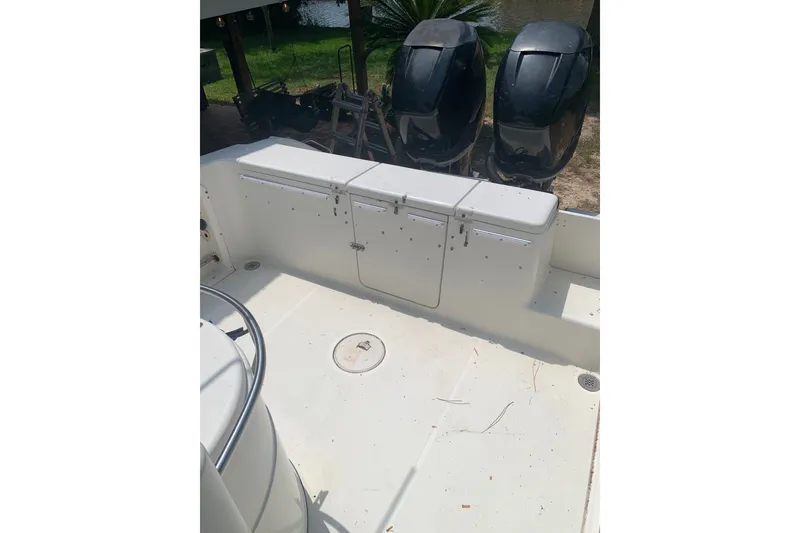 Slide: The Image of 2005 Triton 2895 CC boat interior with dual outboard motors, spacious deck, and storage compartments. - 7