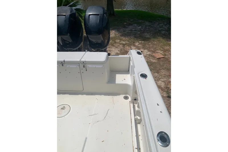 Slide: The Image of 2005 Triton 2895 CC boat deck with dual engines, near a water body. - 8