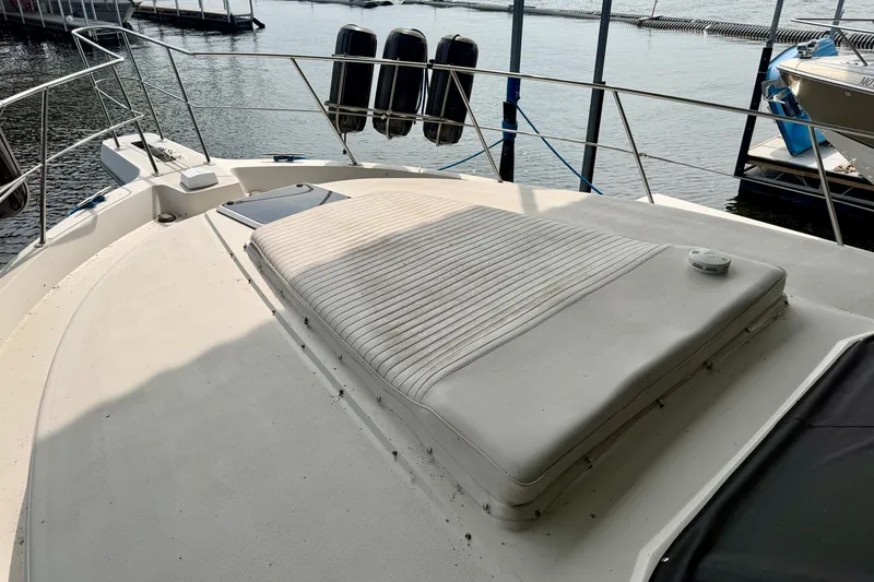 Slide: The Image of 1994 Carver 440 Aft Cabin Motor Yacht deck with cushioned seating, docked at marina. - 2