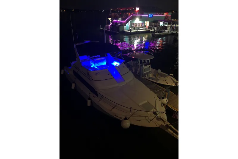 Slide: The Image of 2001 Carver 380 Santego SE yacht illuminated with blue lights at night near a dock. - 20