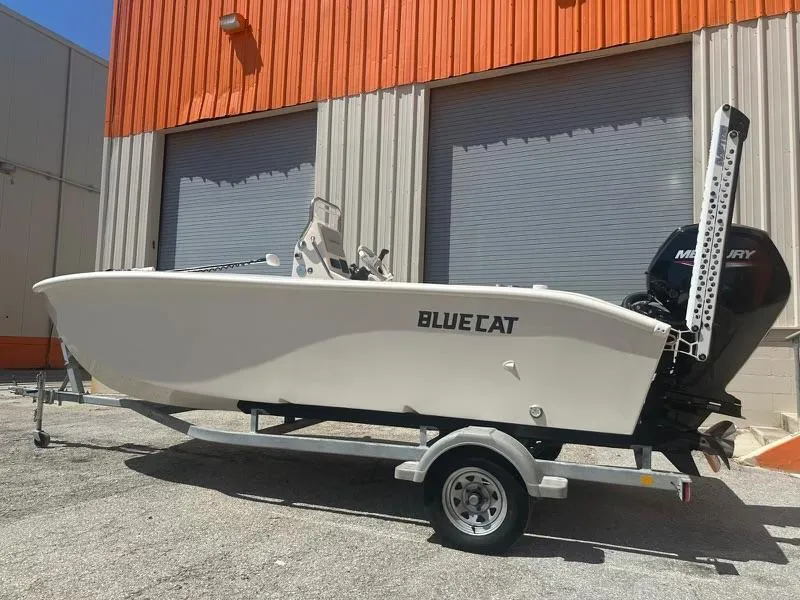 Slide: The Image of 2024 BlueCat 17 boat on a trailer, parked outside a warehouse. - 0