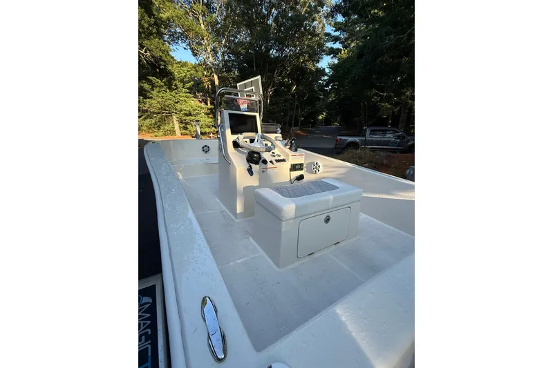 Slide: The Image of 2024 BlueCat 17 boat interior with steering console, seating, and storage, surrounded by trees. - 6