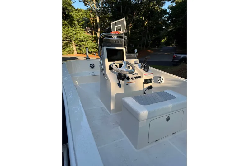 Slide: The Image of 2024 BlueCat 17 boat interior with steering console and seating, set in a wooded area. - 5