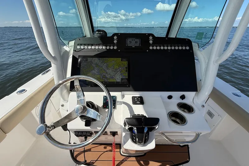 Slide: The Image of 2022 Everglades 273 Center Console helm with steering wheel, navigation display, and ocean view. - 19