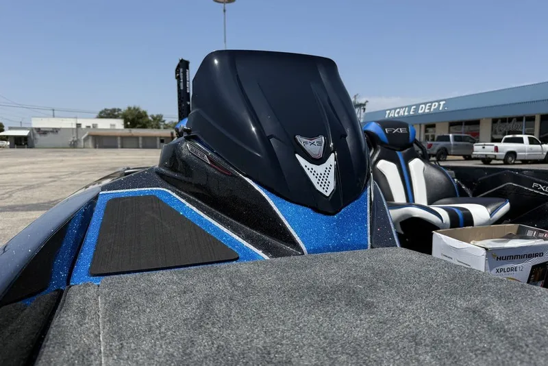 Slide: The Image of 2027 Skeeter FXE20 Limited boat with blue accents, parked near tackle shop. - 16