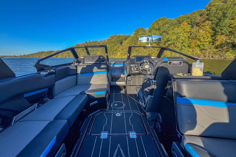 Slide: The Image of 2024 Supra SV 400 boat interior with sleek seating and modern dashboard on a scenic lake. - 29