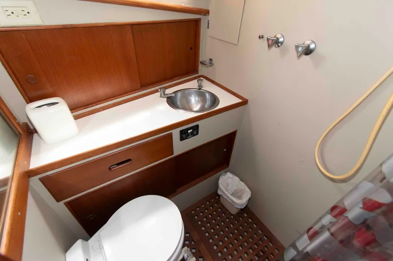 Slide: The Image of 1974 Grand Banks 42 Classic yacht bathroom with sink, toilet, and wooden cabinetry. - 28