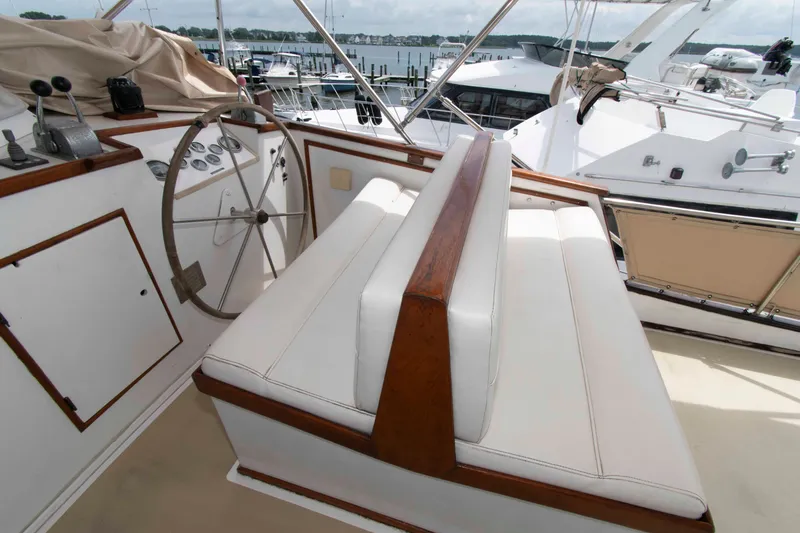 Slide: The Image of 1974 Grand Banks 42 Classic yacht helm with wooden wheel and white seating. - 9