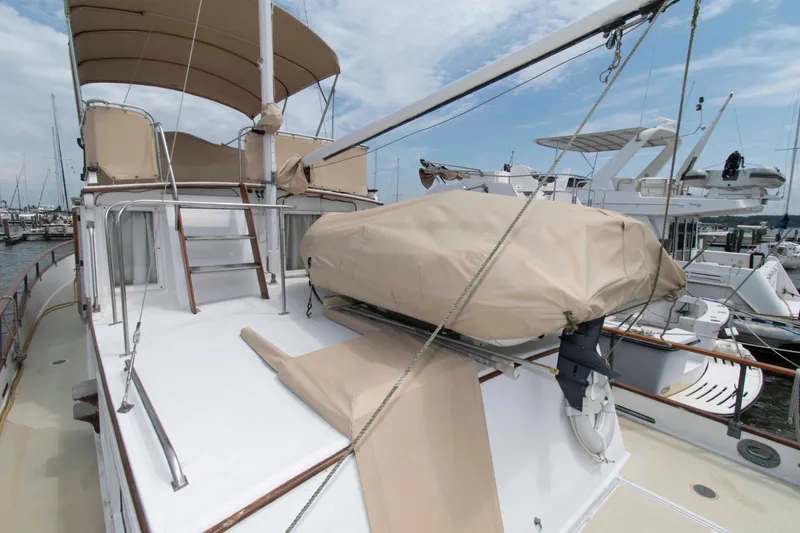 Slide: The Image of 1974 Grand Banks 42 Classic yacht deck with covered equipment and marina backdrop. - 6