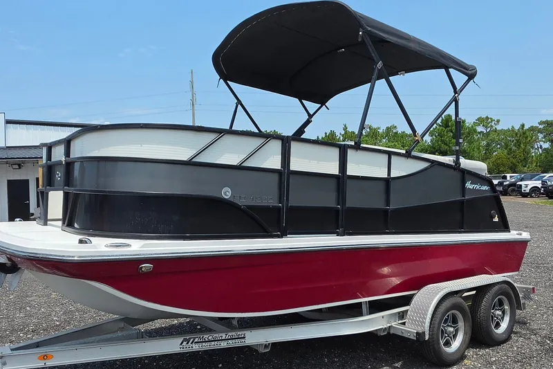 The Image of 2023 Hurricane FunDeck 1960 RE OB boat on trailer, featuring red and black design. - 0