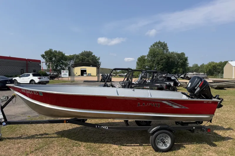 The Image of 2024 Lund WC 16 Tiller boat on trailer, red exterior, parked outdoors. - 0