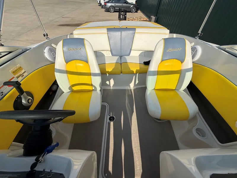 Slide: The Image of The image shows the cockpit of a 2006 Sea Ray 185 Sport boat with yellow and gray seats. - 13