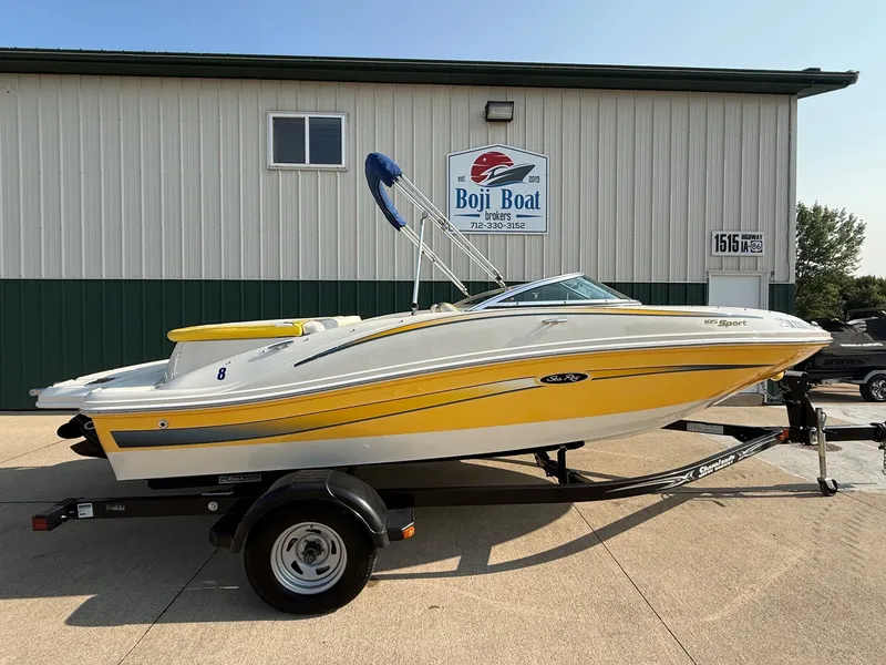 The Image of A yellow 2006 Sea Ray 185 Sport boat on a trailer in front of a building. - 0