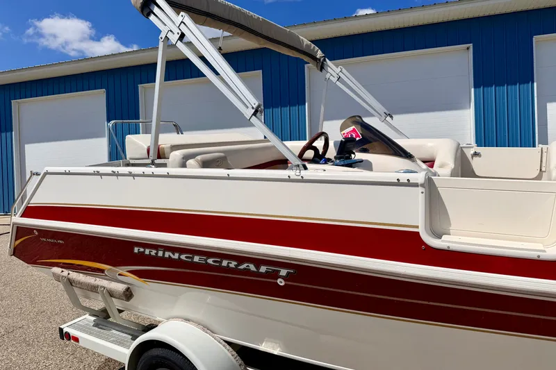 Slide: The Image of 2005 Princecraft Vacanza 210V O/B boat with red and white design, parked near blue building. - 12