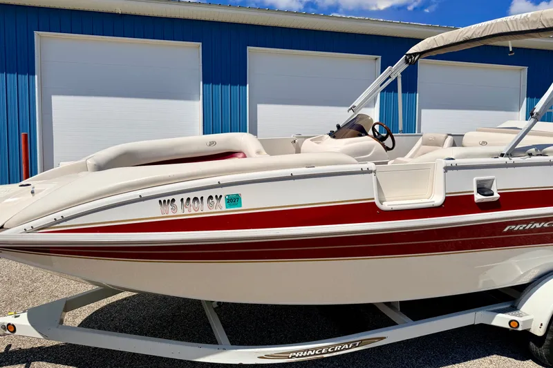 Slide: The Image of 2005 Princecraft Vacanza 210V O/B boat with red accents, parked near blue building. - 16