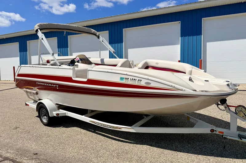 The Image of 2005 Princecraft Vacanza 210V O/B boat on trailer, parked near blue building. - 2