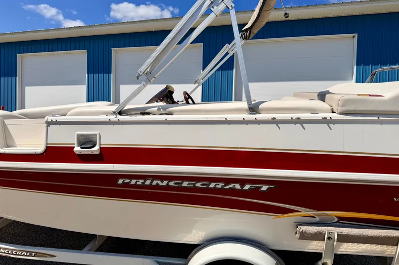 Slide: The Image of 2005 Princecraft Vacanza 210V O/B boat with red and white design, parked near blue building. - 17
