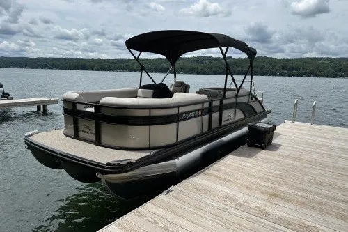 The Image of 2017 Bennington 24SSBXP pontoon boat docked on a serene lake under cloudy skies. - 2