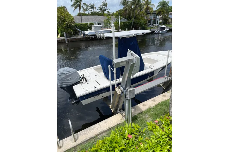 Slide: The Image of 2015 Pathfinder 2200 V Tournament Edition boat docked by a canal with lush greenery. - 3