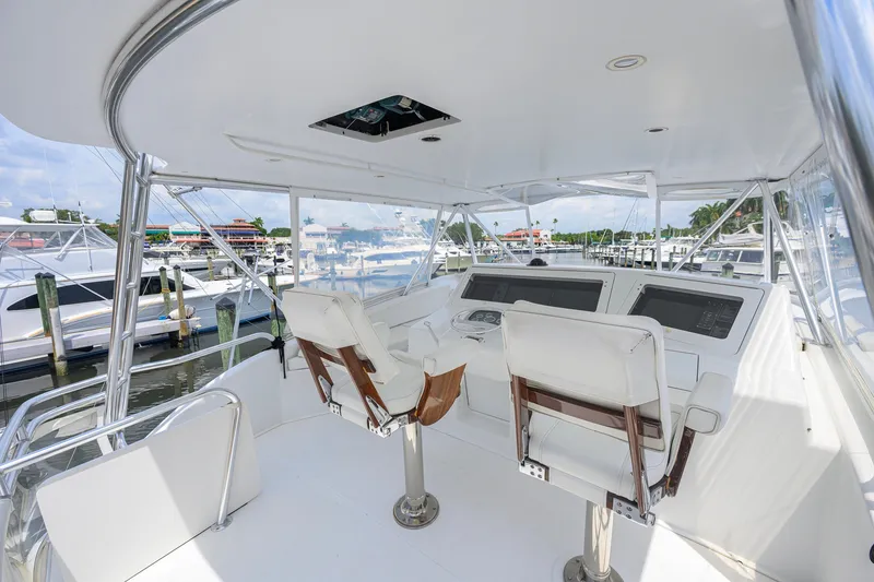 Slide: The Image of 2001 Viking 55 Convertible yacht helm with white seating and marina view. - 27