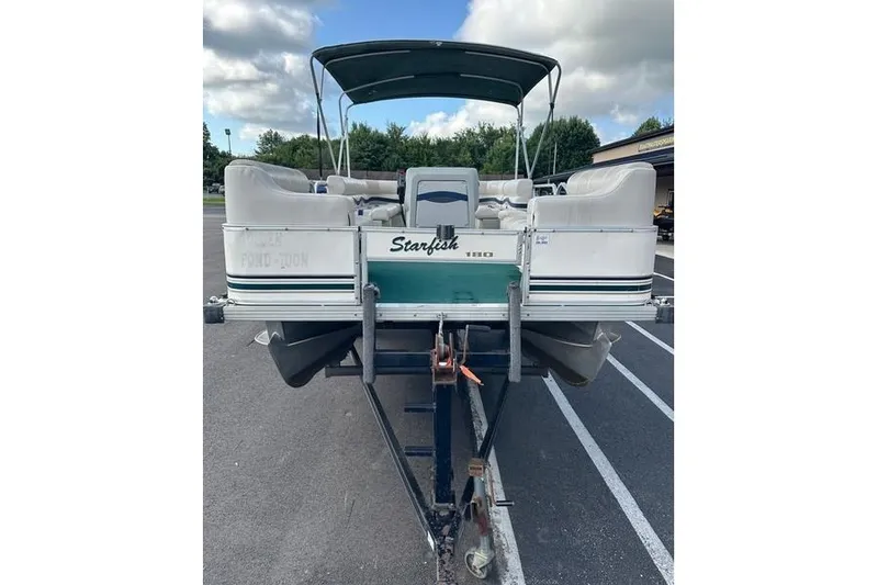 Slide: The Image of 1999 Starcraft Starfish 180 pontoon boat on trailer, parked outdoors. - 4