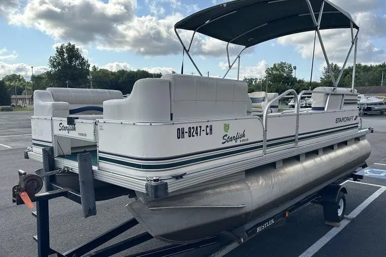 Slide: The Image of 1999 Starcraft Starfish 180 pontoon boat on trailer, parked outdoors under cloudy sky. - 12