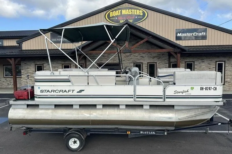 The Image of 1999 Starcraft Starfish 180 pontoon boat on trailer, parked outside Boat Masters Marine. - 1