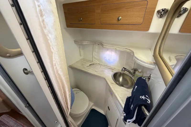Slide: The Image of 2015 Rinker 340 Express Cruiser bathroom with sink, toilet, and wooden cabinets. - 33