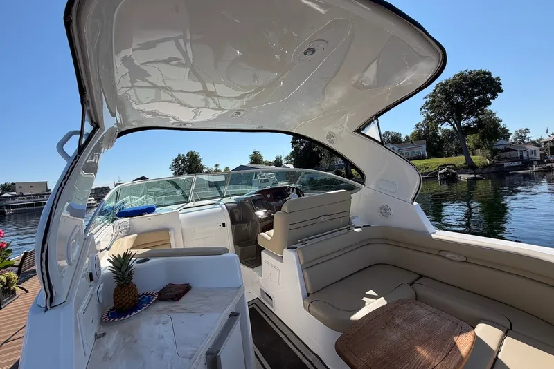 Slide: The Image of 2015 Rinker 340 Express Cruiser interior with seating, docked by a scenic waterfront. - 17