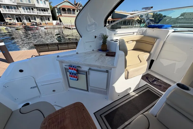 Slide: The Image of 2015 Rinker 340 Express Cruiser interior with seating, kitchenette, and marina view. - 22