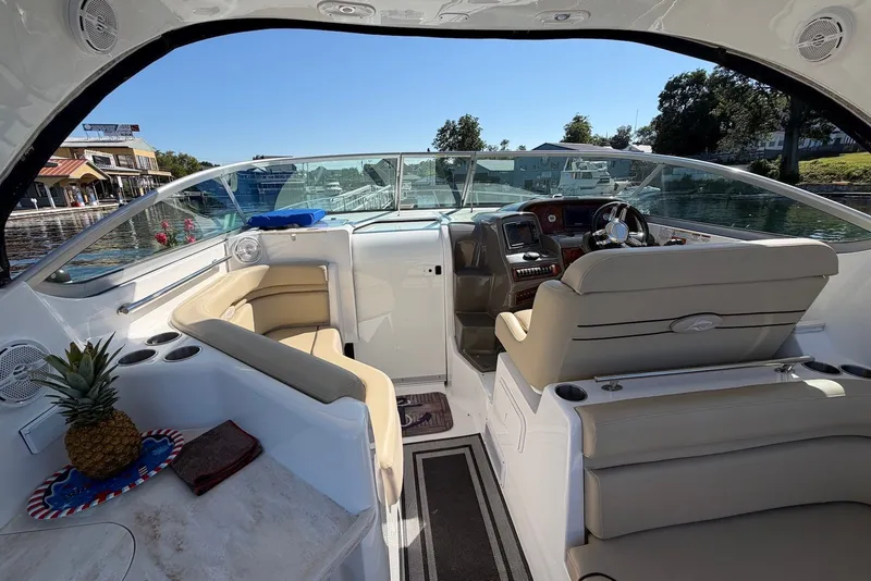 Slide: The Image of 2015 Rinker 340 Express Cruiser interior with seating, steering console, and waterfront view. - 18