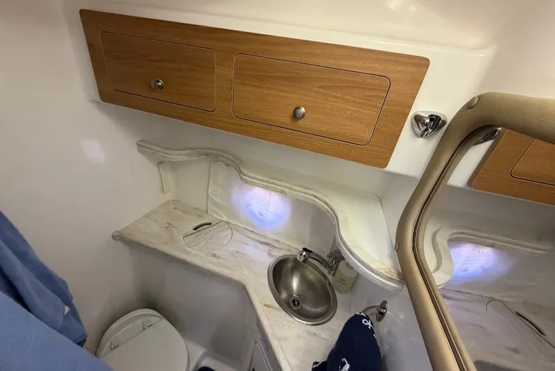 Slide: The Image of 2015 Rinker 340 Express Cruiser bathroom with sink, toilet, and wooden cabinets. - 34
