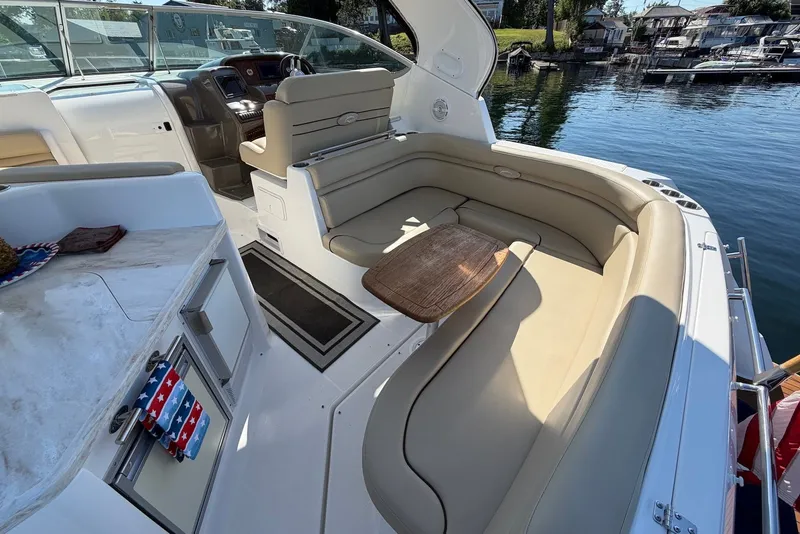 Slide: The Image of 2015 Rinker 340 Express Cruiser interior with seating and table, docked by the water. - 16