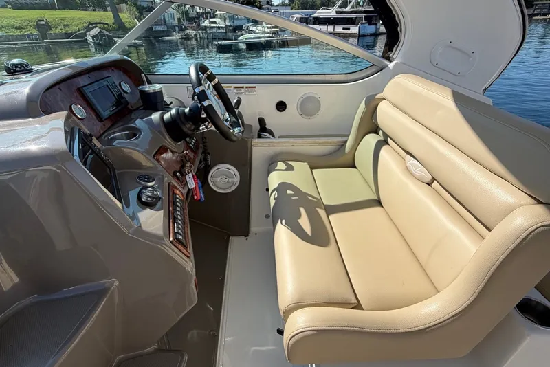 Slide: The Image of 2015 Rinker 340 Express Cruiser helm with beige seating and control panel. - 21