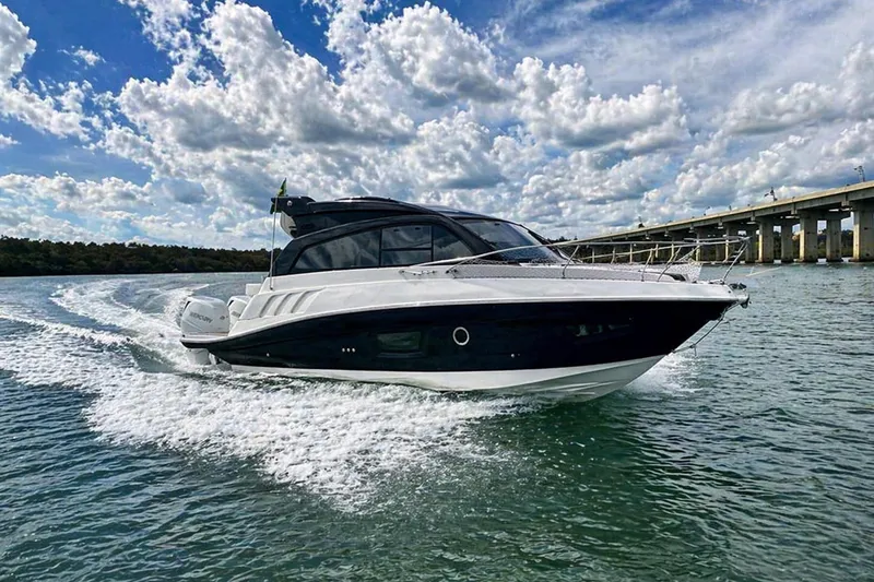 Slide: The Image of 2026 Hanover 355 boat cruising on water under a cloudy sky near a bridge. - 1