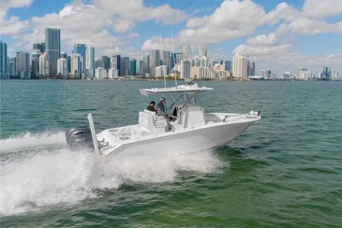 Slide: The Image of SeaHunter 25 Floridian 2027 cruising on the water with a city skyline in the background. - 2