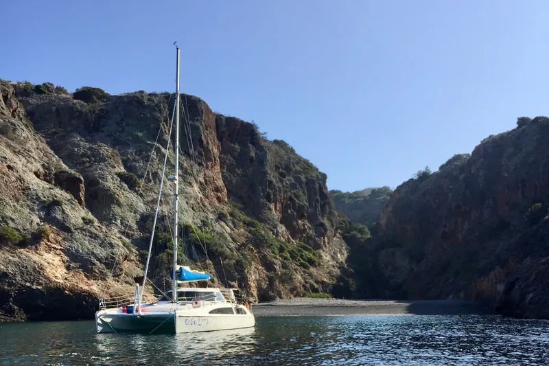 Slide: The Image of Sailing catamaran Seawind 1160 (2009) anchored near rocky cliffs and serene cove. - 5