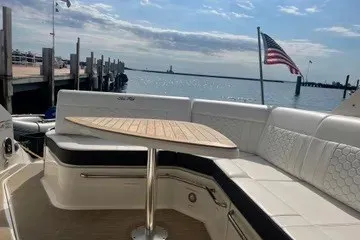 Slide: The Image of 2020 Sea Ray Sundancer 320 yacht with seating area and American flag, docked by the water. - 5
