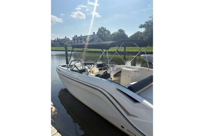 The Image of 2023 Bayliner DX 2200 boat docked on a sunny day, featuring sleek design and canopy. - 0